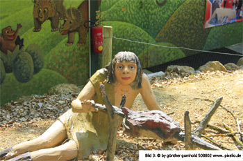 Steinzeitmensch grillt am Grillspieß ein Tier